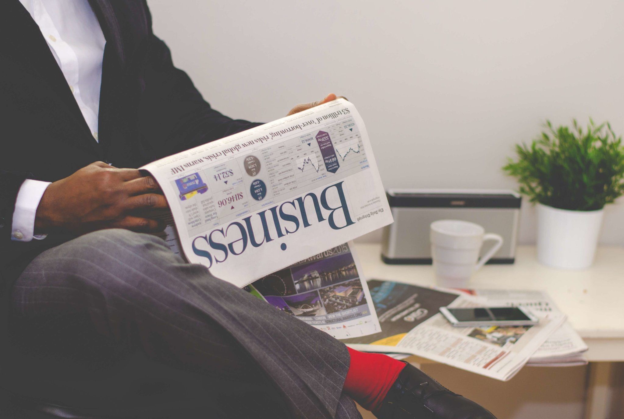 Home Businessman reading a financial newspaper at a desk, highlighting finance and commerce theme.